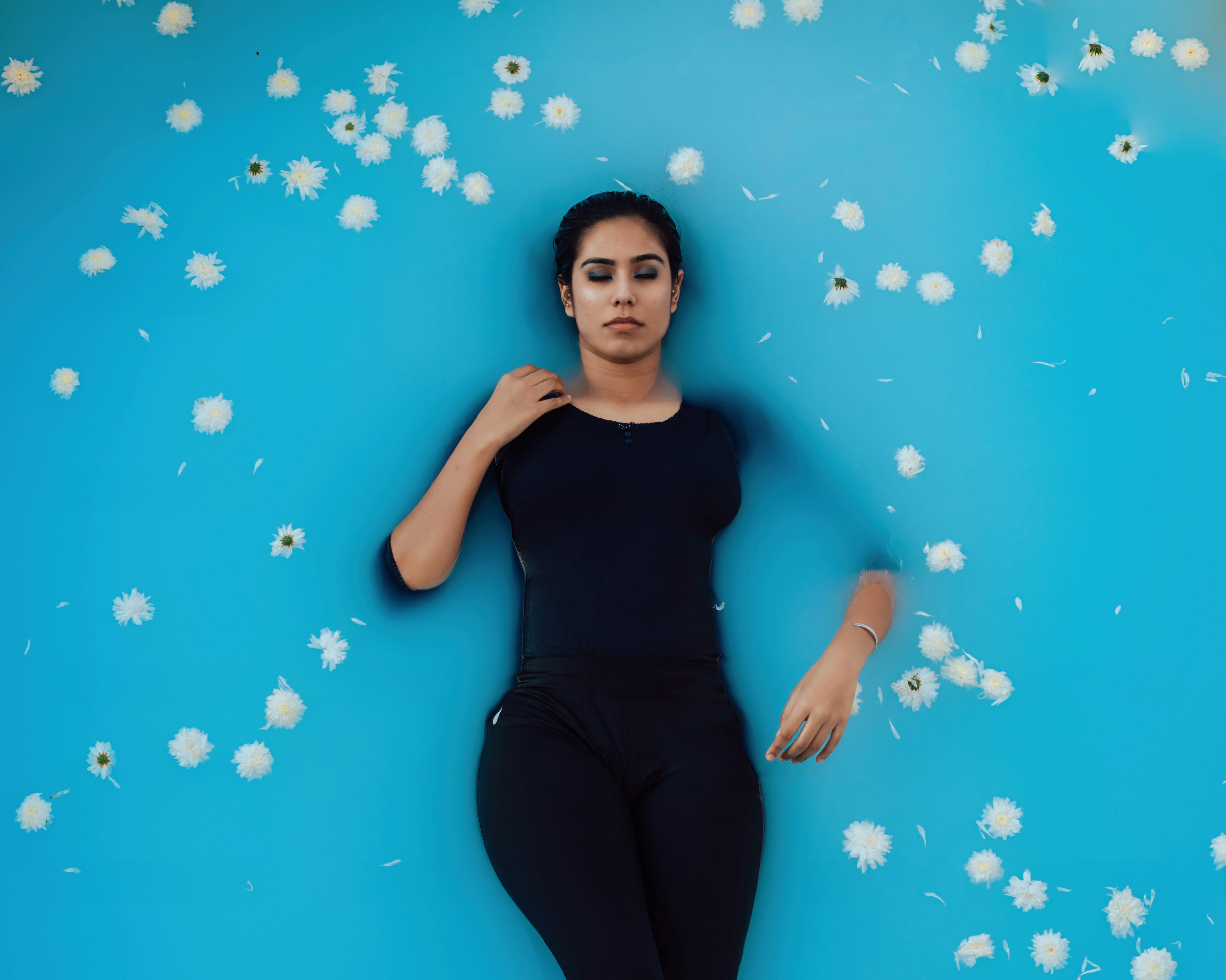 woman in black tank top and black leggings lying on blue and white polka dot wall